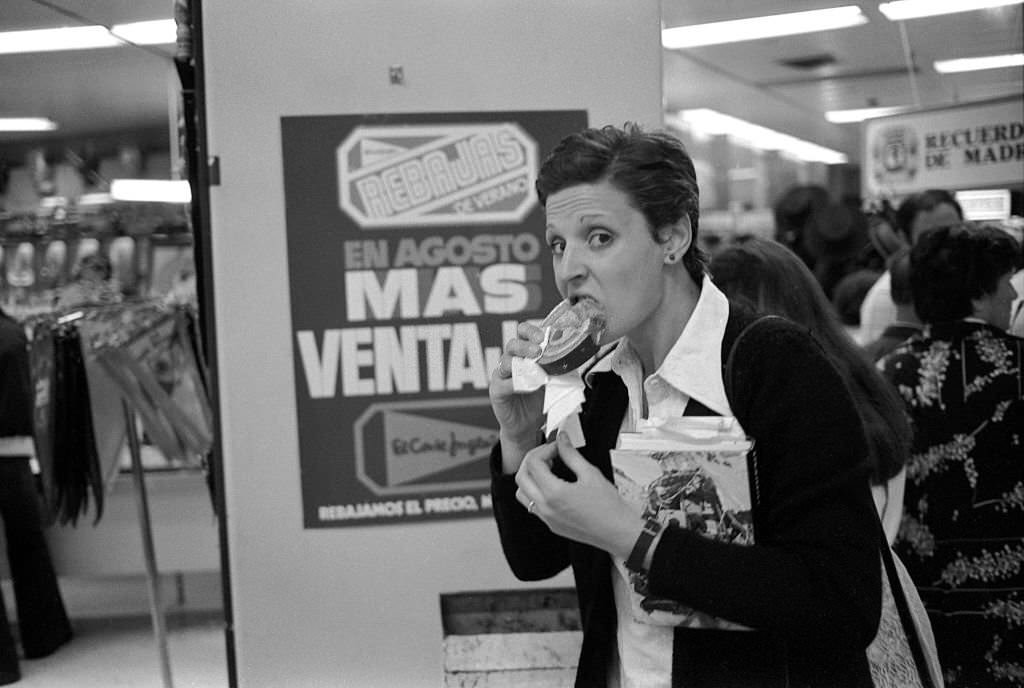 Woman eating a pastry in a department store in Toledo, Spain, August 21, 1977.