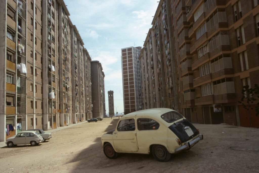 Fiat 500 car dented and parked between buildings in the Cornella district, May 1977, Barcelona, Spain.