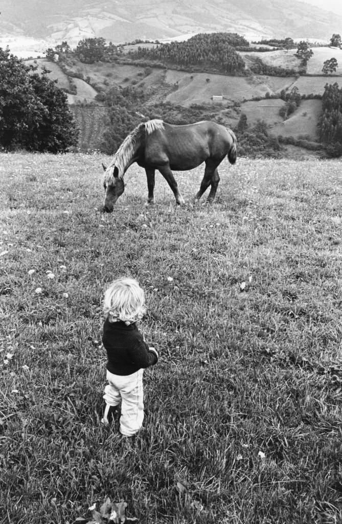 Child observing a horse, in the 1980s, Spain.