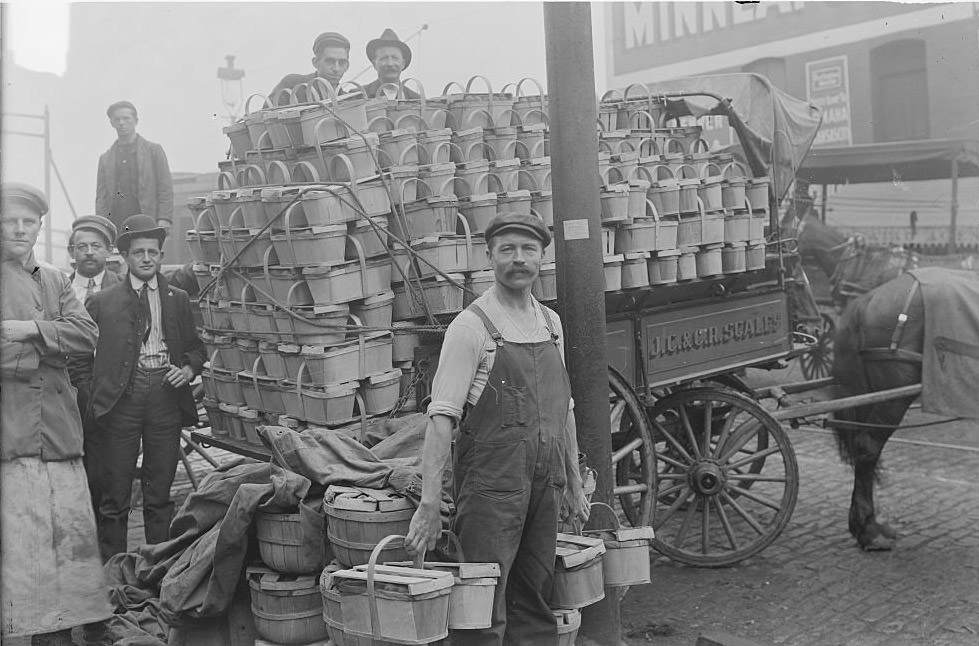 Several men standing around a cart filled with baskets of peaches in the South Water Street Market in Chicago, Illinois, 1902