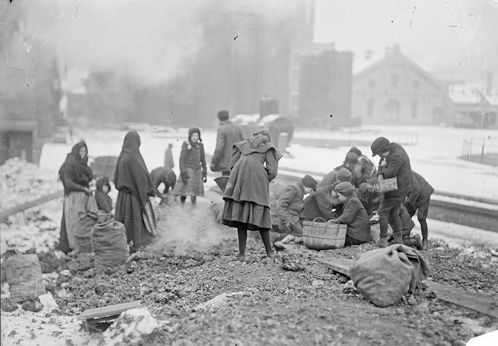 Women and children picking up coal from the ground at the coal yards, Chicago, Illinois, 1902.