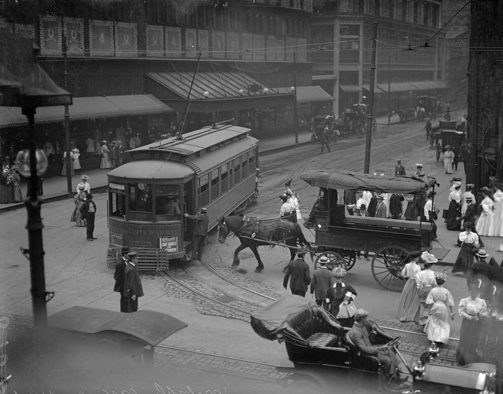 Street traffic, including a streetcar, horse drawn wagon, automobile and pedestrians, crossing the intersection of State and Madison Streets, Chicago, 1906