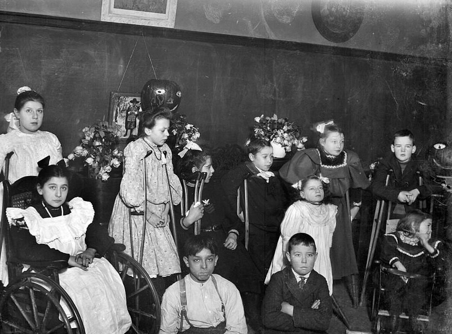 Children with handicaps assembled in front of a blackboard in a classroom, Chicago, Illinois, 1905.