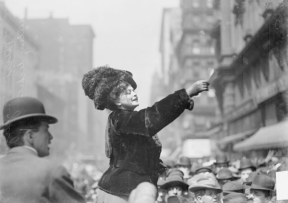 Trixie Wrigley standing above a crowd gathered in the street around her, selling tickets to a sporting event, Chicago, Illinois, 1905.