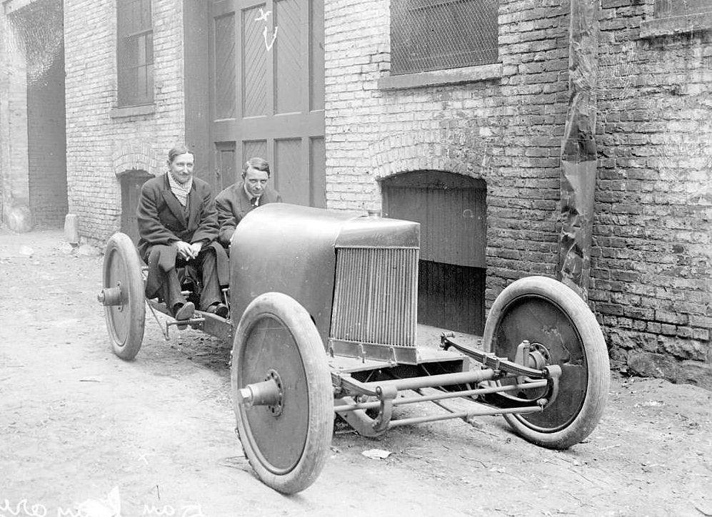 Group portrait of Barney Oldfield and Dan Canary, motorists, sitting in a car parked next to a garage in Chicago, Illinois, 1905.