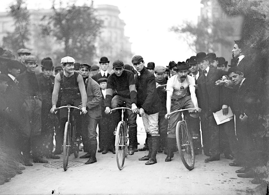 Cyclists, J. E. Gill, C. A. Linde, Ed Bukowski , positioning on their bicycles in front of a crowd on North Michigan Avenue in the Near North Side community area of Chicago, Illinois, 1901.