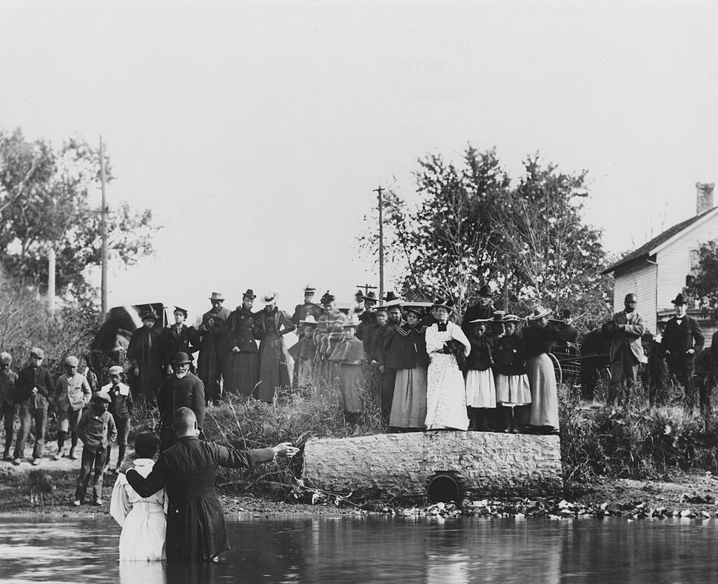 A priest baptizes a congregant in a ceremony at Fox River, at the foot of Lake Street, 1900.