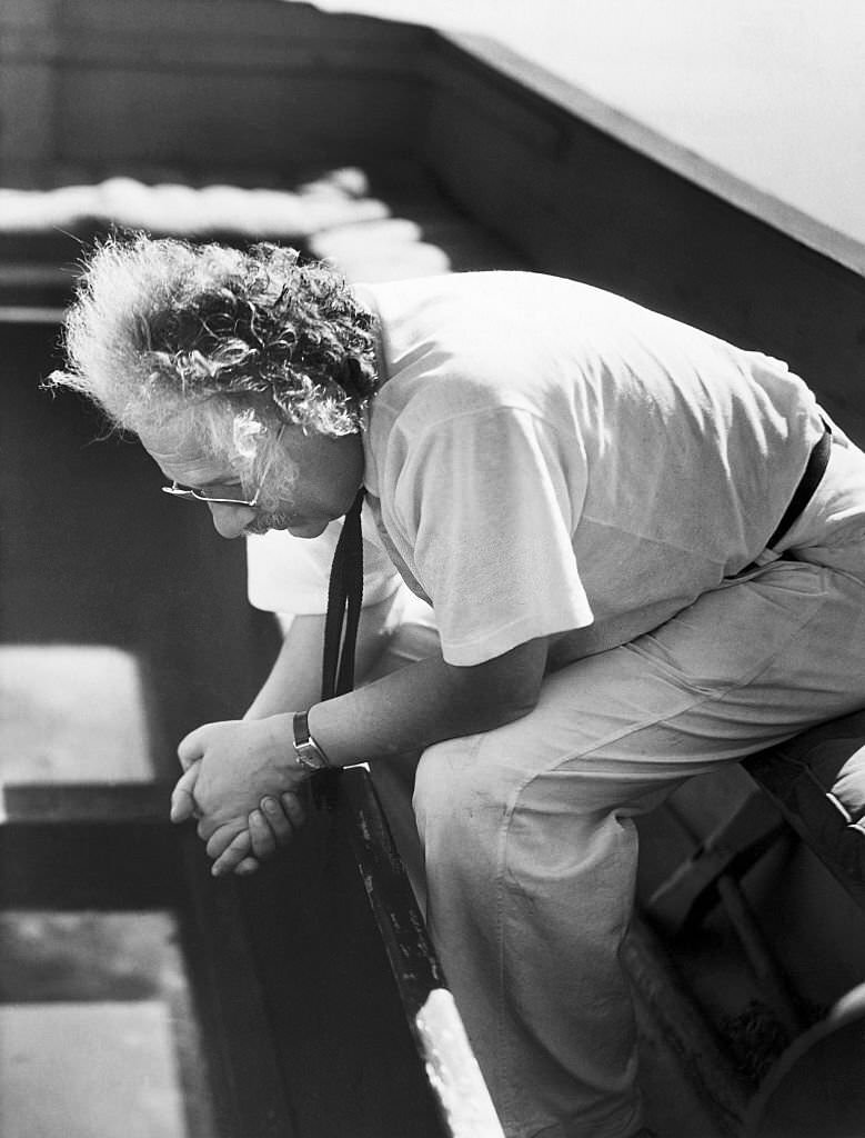 Albert Einstein sitting pensively on the deck of his sailboat.