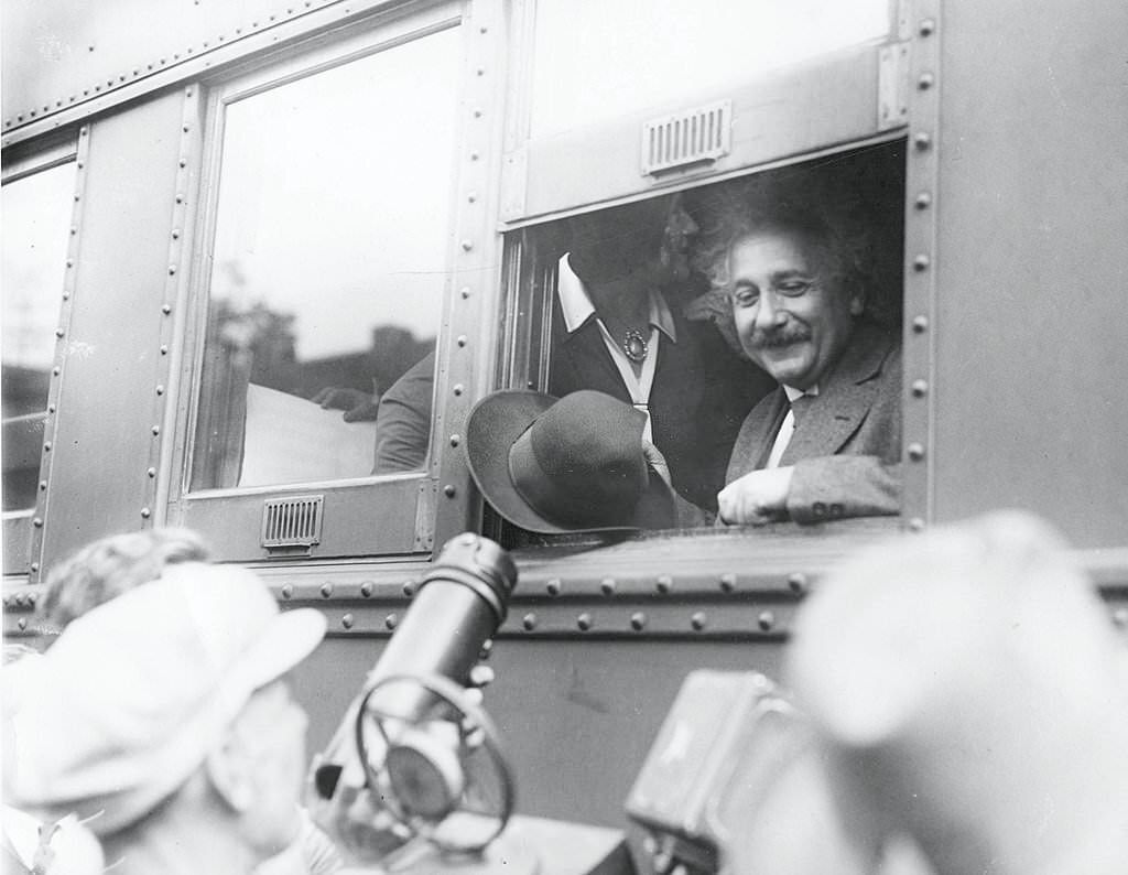 Albert Einstein smiles at supportors and newsmen out of the window of a train, Chicago, Illinois, early 1930s.