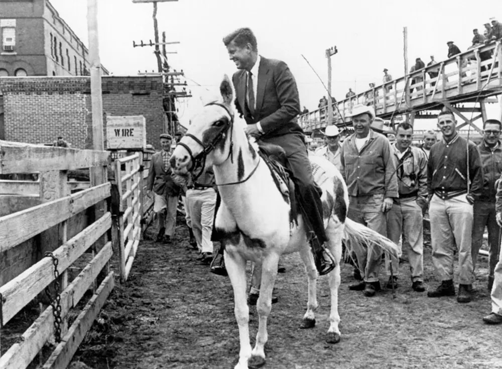 John F. Kennedy rides a mule during a campaign visit to the stockyards at Sioux City, Iowa, 1960.