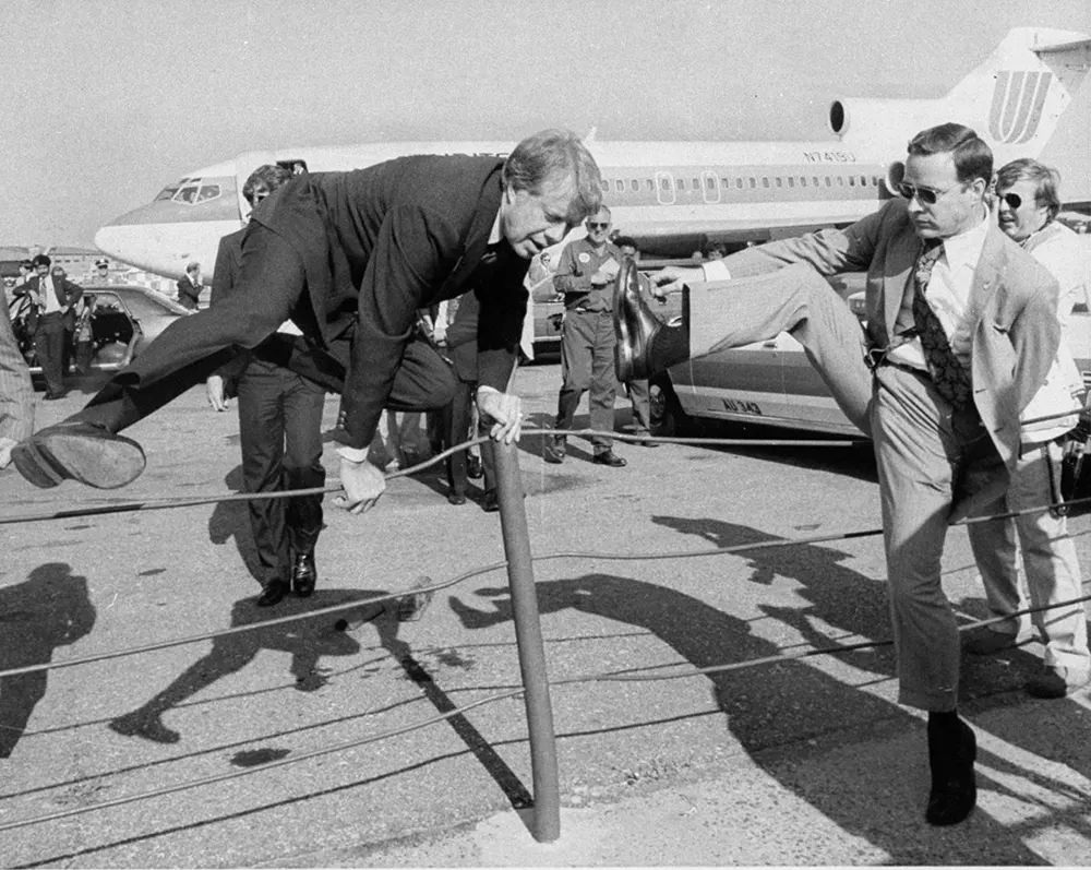 Jimmy Carter and an aide hop a fence at LaGuardia airport in New York City, 1976.