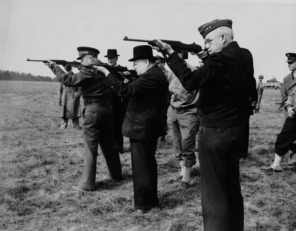 Dwight D. Eisenhower, Winston Churchill and Gen. Omar Bradley fire carbines during a tour of an army camp in England, 1944.