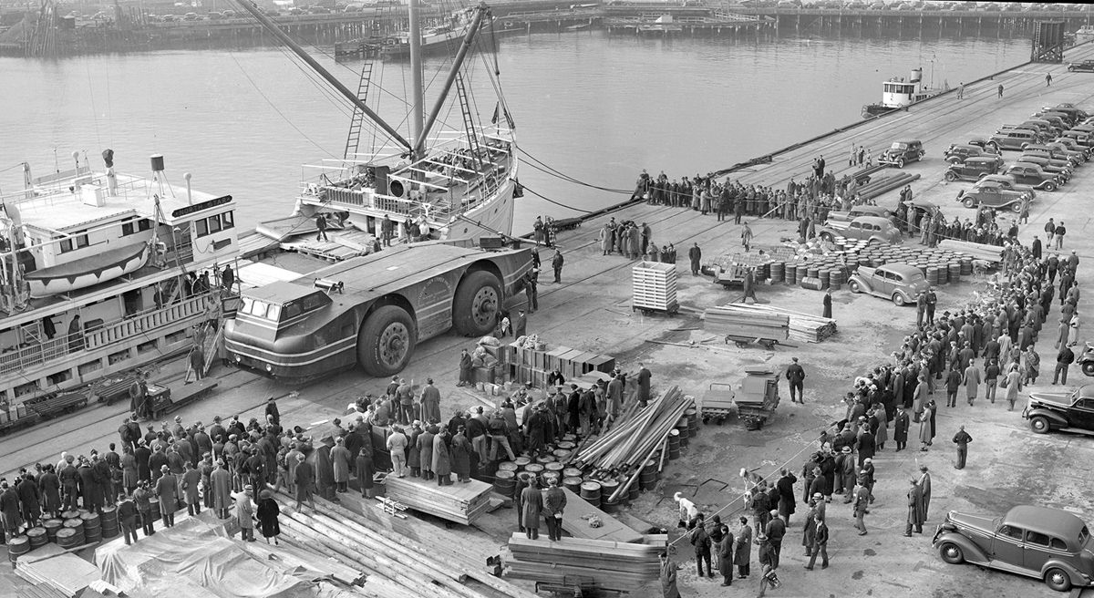 Onlookers watch as expedition members prepare to load the massive Snow Cruiser onto the deck of the North Star in November of 1939.