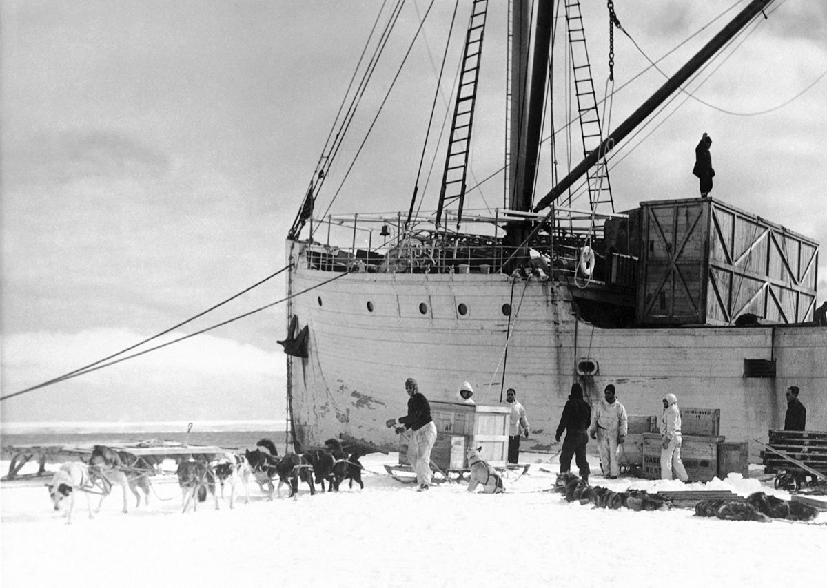 Members of Rear Admiral Byrd’s Antarctic expedition are hard at work loading sleds with supplies from the ship, North Star, (in the background), at the party’s west base on March 16, 1940.