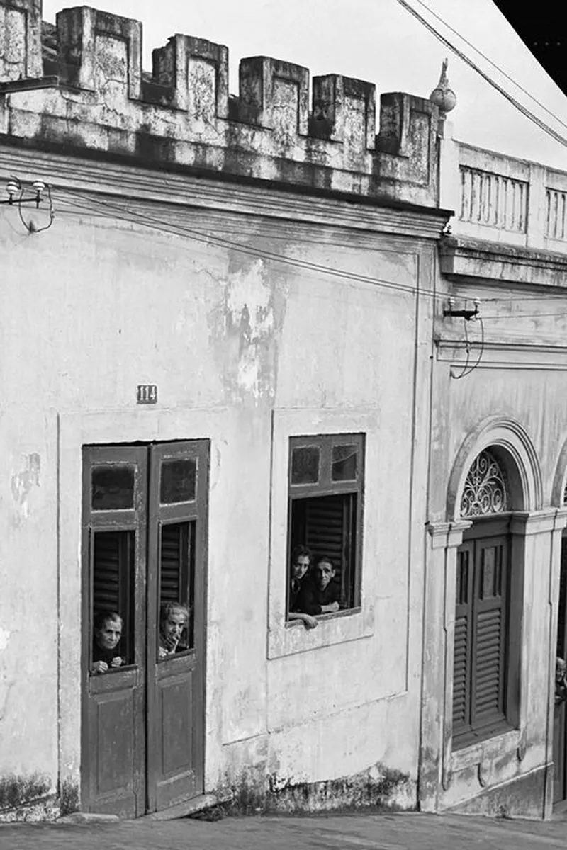 Women peer from a tenement house.