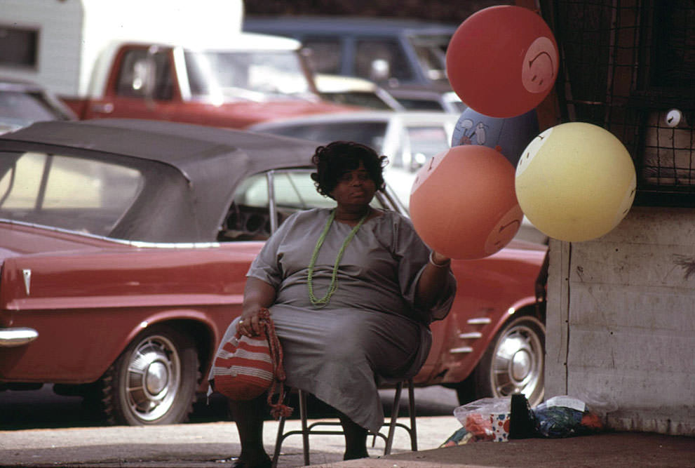 Woman selling “Have A Nice Day” balloons on a Chicago South Side street corner at Sox Park Baseball Field, June 1973.