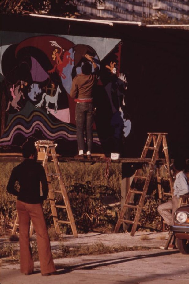 Artist Ron Blackburn painting an outdoor wall mural at the corner Of 33rd and Giles Street.