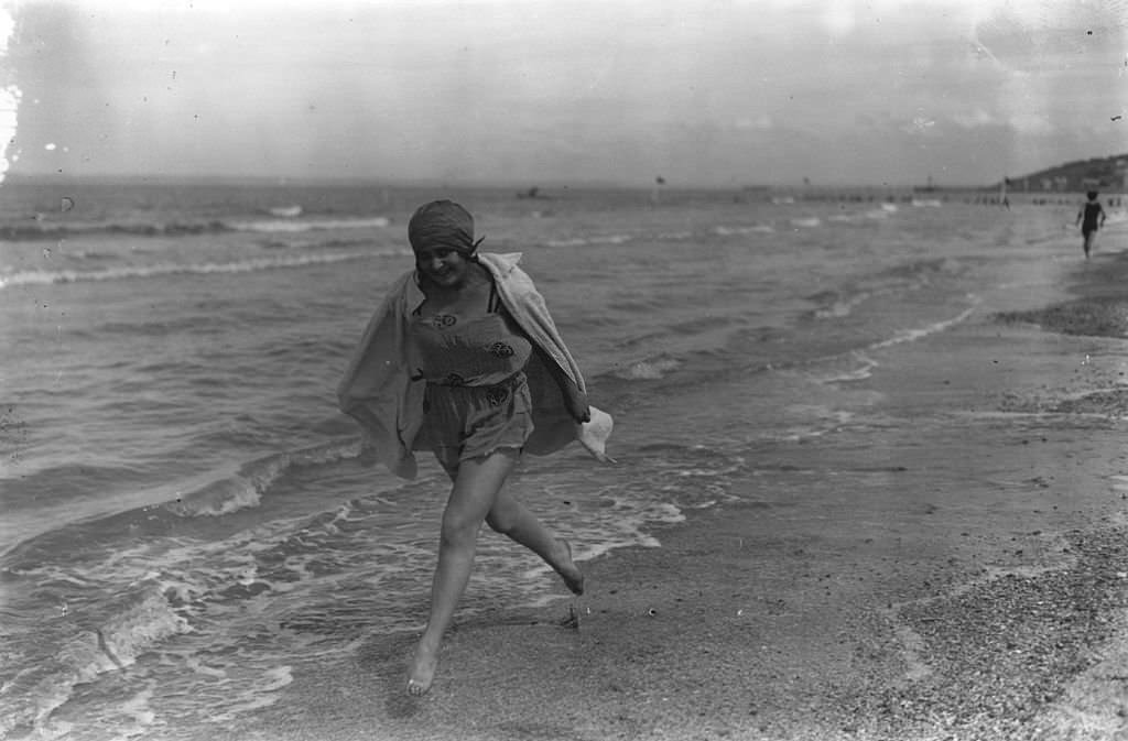 A young woman running along the water's edge at Deauville, 1924