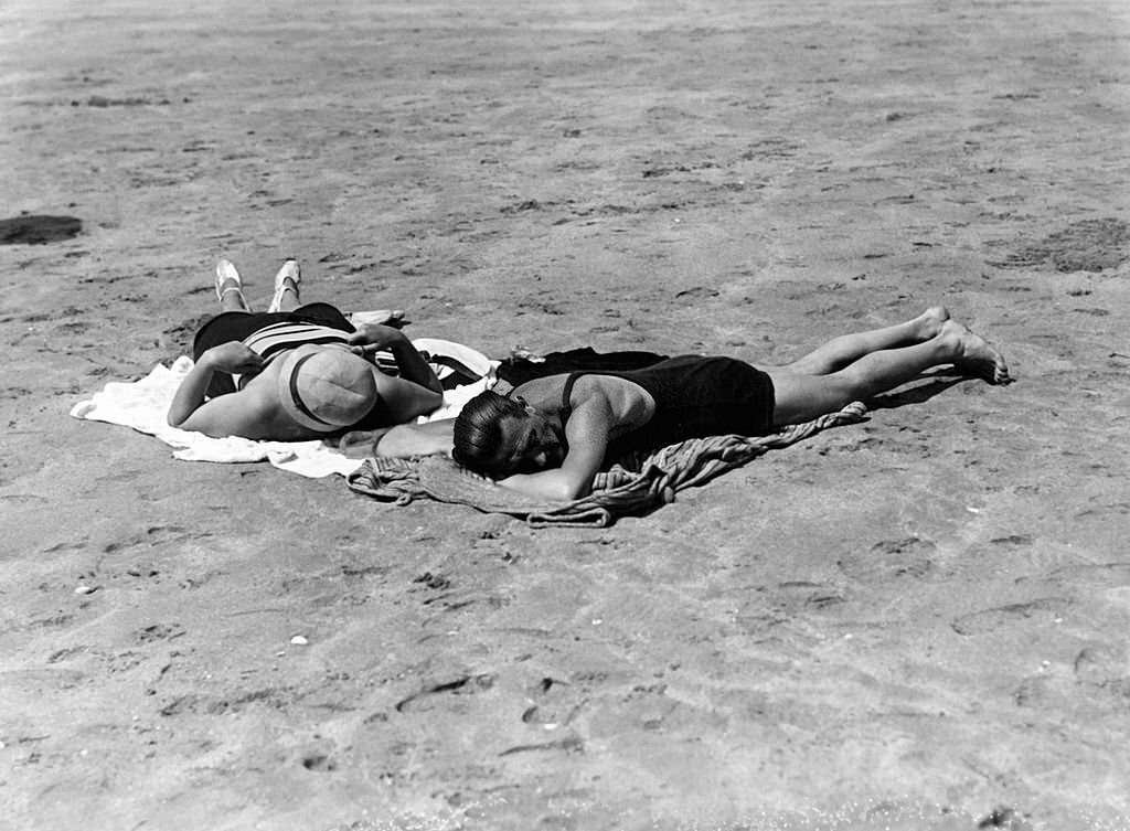 Women sunbathing on the beach in July 1929 in Deauville, France.