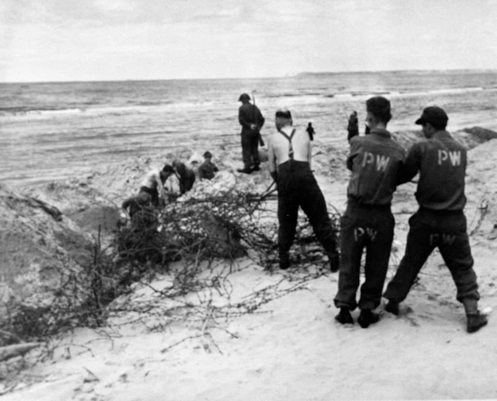German prisoners of war line under the watch of English soldiers, in Deauville, France in 1946.