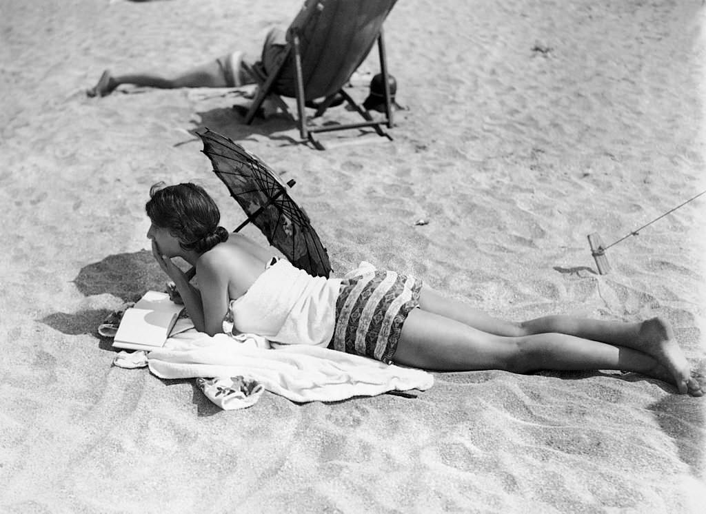 A young woman reading on the beach in Deauville, 1920
