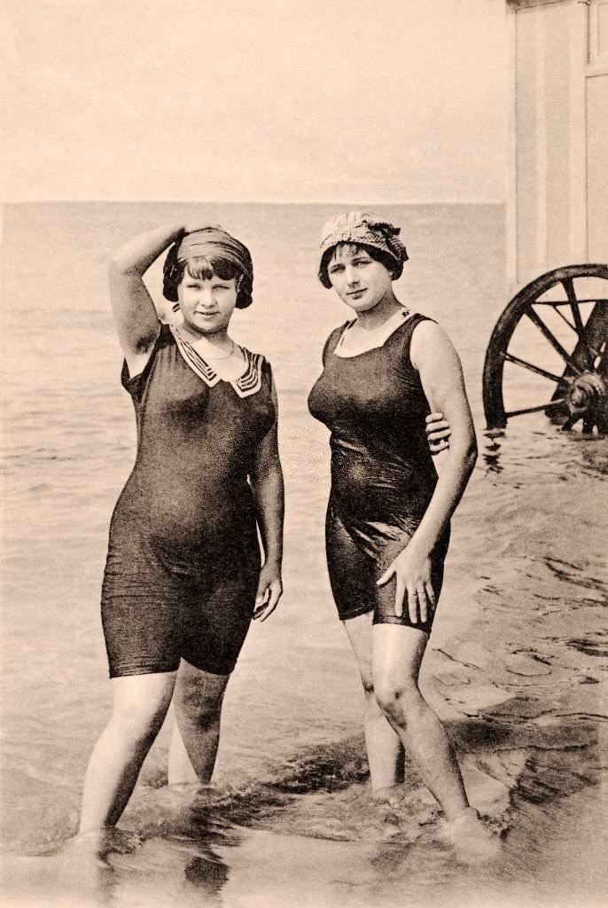 Two young women wearing bathing costumes with a bath cart behind, 1920.