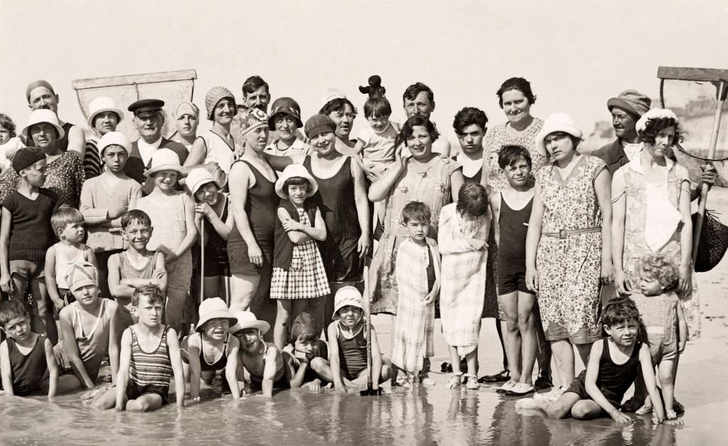 A group of holidaymakers, several with nets, posing on the beach at Deauville, 1920