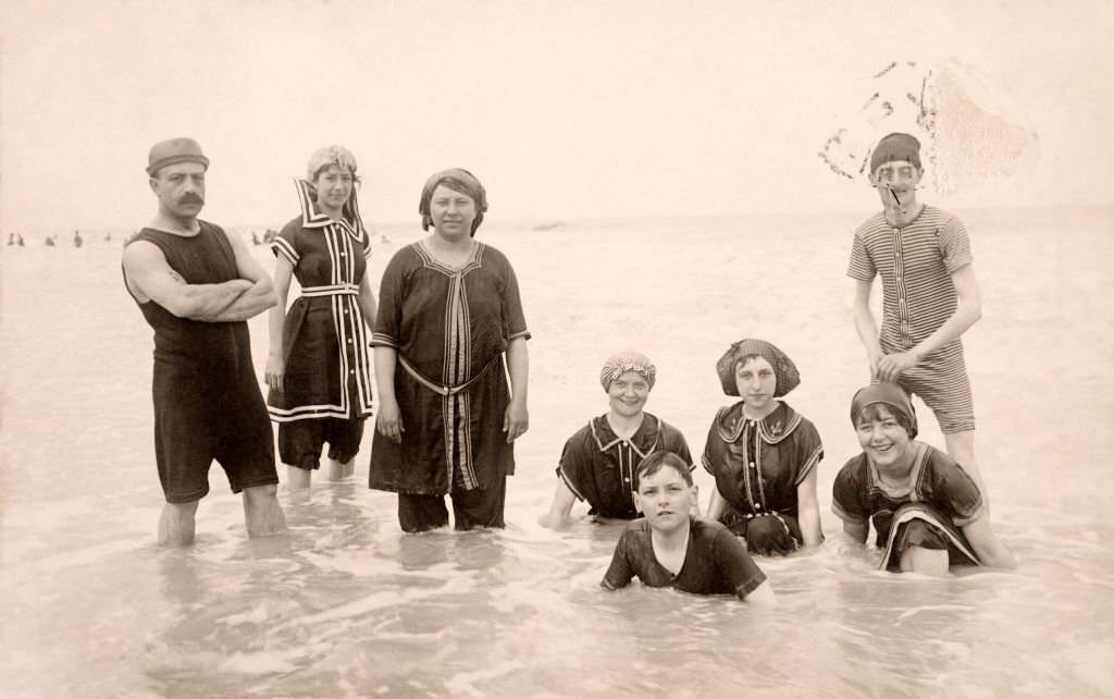 A small group of people wearing swimming costumes paddling at Deauville, 1910