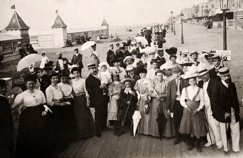 A large group of people wearing the latest fashion on the promenade at at Deauville, 1910