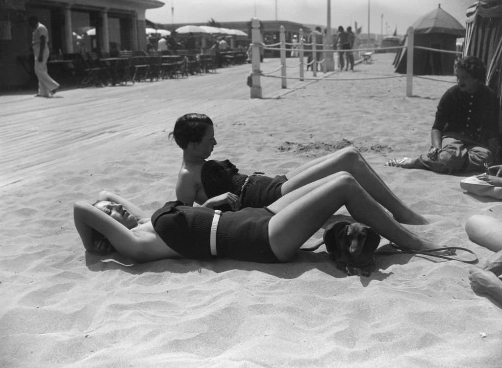 Two young women sunbathe, lying on the sand of the beach at Deauville, 1935