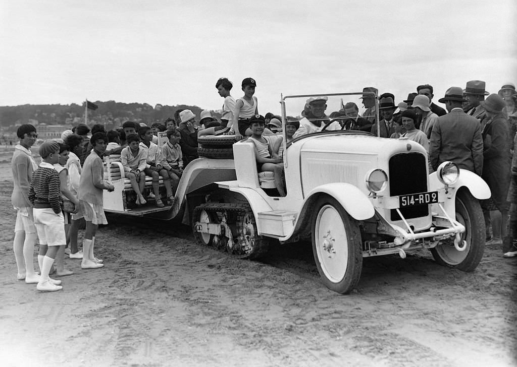 Children going for a beach drive in a trail towed by a tracked Citroen in August 1929 in Deauville, France.