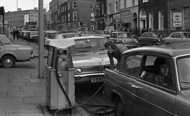 A young man filling up his car from a street petrol pump, April 1975.