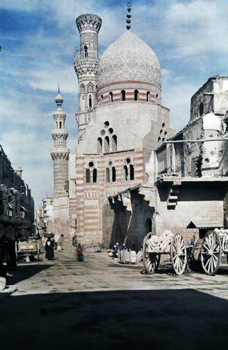 Street view of a mosque with a wall covered in blue tiles.