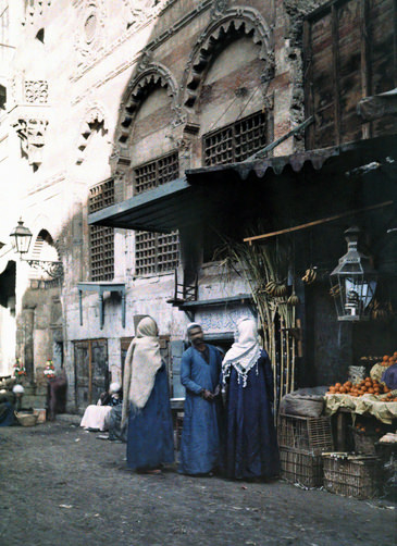 Man and two women stand at his homegrown fruit booth in Cairo.