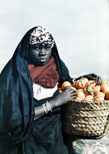 Woman posing with a basket of mandarins or tangerines.