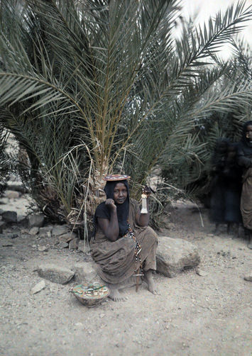 Woman sitting on a rock with jewelry beside her.