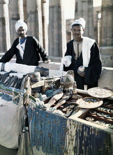 Two men stand in front of souvenir booths in the street of Cairo.