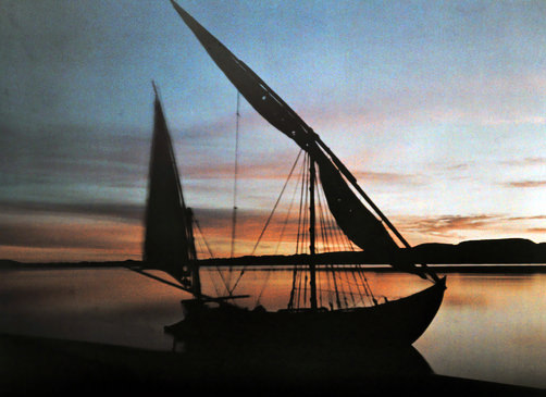 Boat sitting still in the water at sunrise.