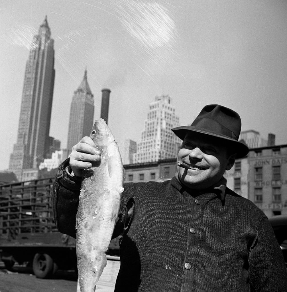 Fisherman holding a fish at the Fulton Fish Market. New York City, 1943.