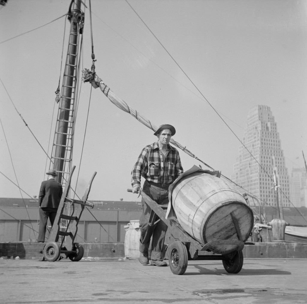 Dock stevedore at the Fulton fish market moving a barrel of codfish. A