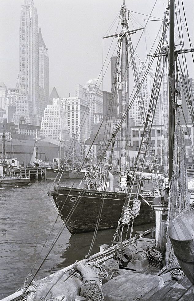 Fulton Street Fish Market, showing some of the fishing boats, and beyond, the spires of Manhattan, 1920s