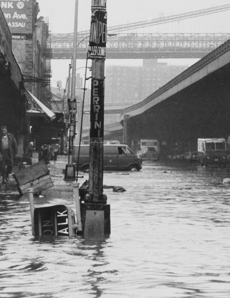 Pedestrians at the Fulton Street Fish Market look as if they need a bridge after heavy wind whipped rains hit the metropolitan area, 1930s