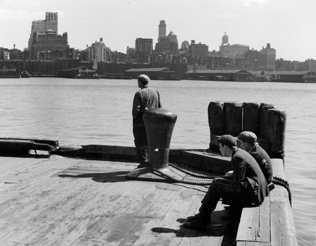 Men sitting on pier near Fulton Fish Market in New York City, 1955.