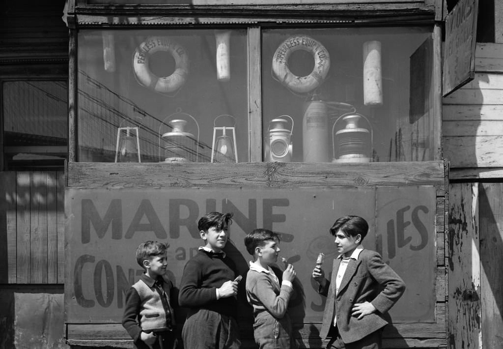our boys, three with popsicles, stand in front of a nautical supply shop (the Peerless Equipment Company, at 189 South Street) in the Fulton Fish Market, 1946.