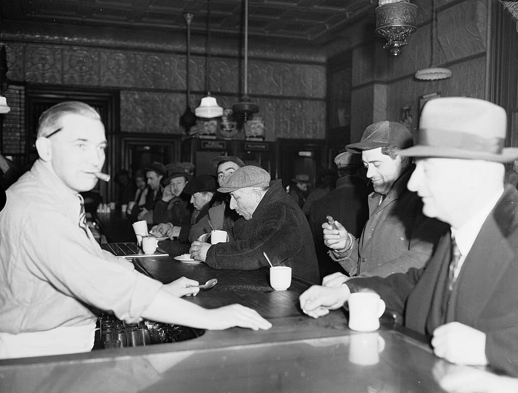 A group of men in coats and caps eat and drink as they sit at the bar in an establishment frequented by fisherman in the Fulton Fish Market area of downtown Manhattan, 1943