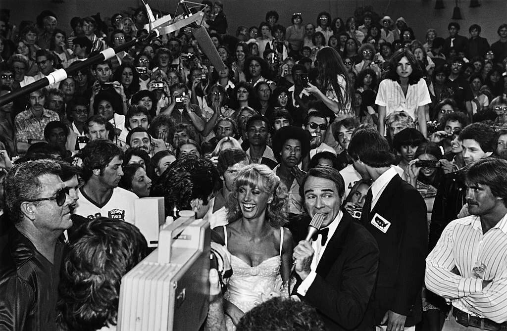 Singer and actress Olivia Newton-John is interviewed by red carpet emcee Army Archerd at the 1978 Hollywood, California film premiere of "Grease".