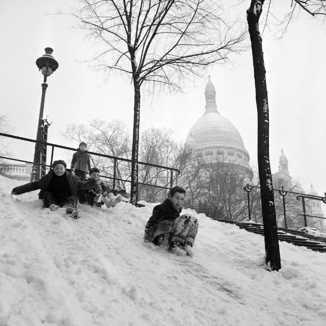 Children slide in the snow on the Montmartre hill in Paris, February 1963.