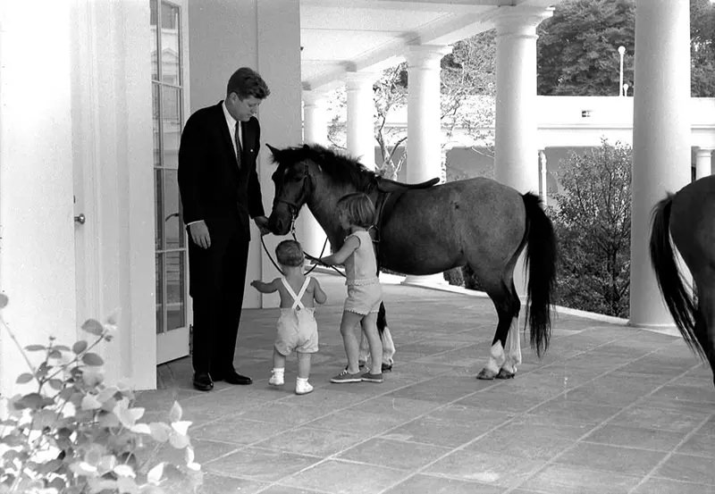 President Kennedy, John Jr. and Caroline play with Macaroni and Tex.