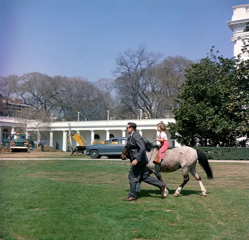 Secret Service agent Bob Foster leads Caroline Kennedy on a ride with Macaroni.
