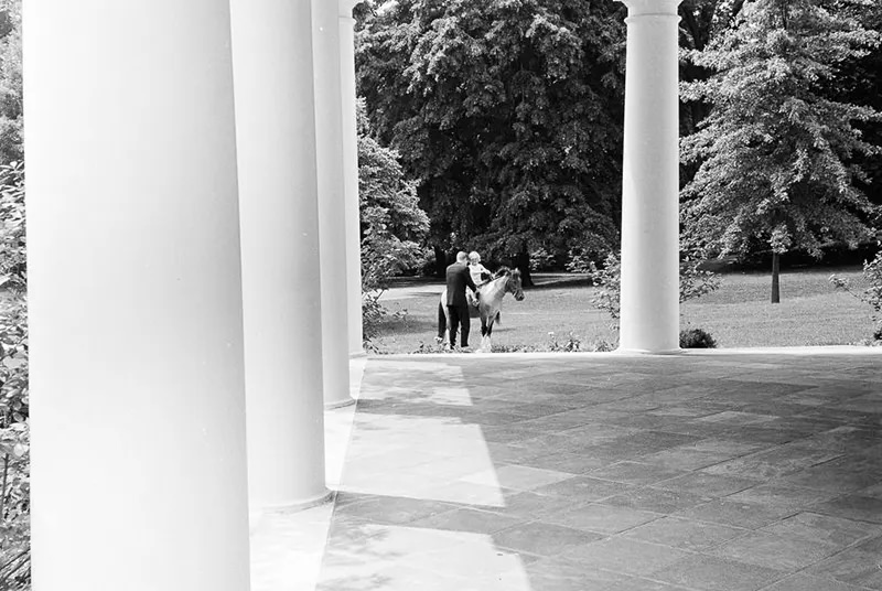 President John F. Kennedy adjusts Caroline’s saddle.